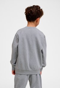 Grå sweatshirt med långa ärmar, ribbade muddar och midjeband. Mjukt tyg, avslappnad passform, enkel design utan synliga mönster eller accenter.