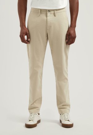 Light beige cotton chinos with a straight-leg fit. Features a button closure, minimal stitching, and worn with white sneakers.