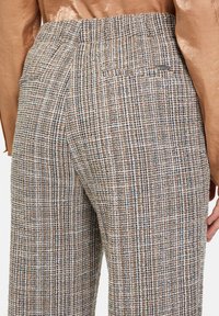 Woven, plaid trousers in earthy tones with blue accents. Elastic waistband, relaxed fit, and a back pocket detail. Textured fabric.