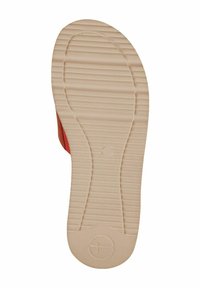 Scarpa rossa con superficie texturizzata, dotata di una suola piatta e gommosa beige con scanalature per la presa e un logo circolare vicino al tallone.