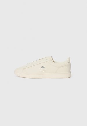 Cream-colored sneaker with a smooth texture, rounded shape, lace-up design, subtle perforations, and a silver logo on the side.