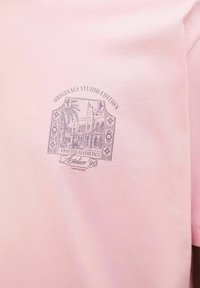 Lyserød bomulds T-shirt med et detaljeret gråt grafisk print med arkitektonisk design og teksten "Crafted Aesthetics Atelier 90."