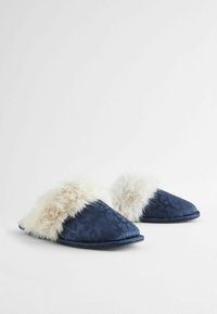 Mørkeblå slippers med et tekstureret dyreprint, der har en blød faux fur kant i lys beige, spids tå-udformning og fleksibel sål.