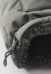 Gant d'hiver gris avec un cordon élastique réglable et une doublure polaire noire douce pour l'isolation et le confort.