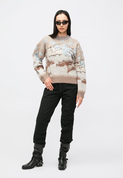 Beige, kék és barna mintás pulóver, puha anyagból. Fekete, testhez simuló nadrággal és térdig érő fekete csizmával párosítva.