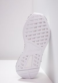 Vit sneaker sula med en texturerad mönster, med en triadisk rutnätsdesign. Inkluderar präglad logotyp och subtila färgaccenter.