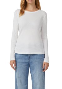 Langsleeve witte blouse van lichtgewicht stof, met een ronde halslijn en rechte zoom, gecombineerd met lichtblauwe jeans.