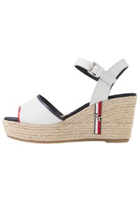 Vit lädersandalett med kilklack och rem, espadrille-stil med jute-mellansula, marinblå foder och röd accentrand. Har en metall-logotypdetalj vid hälen.