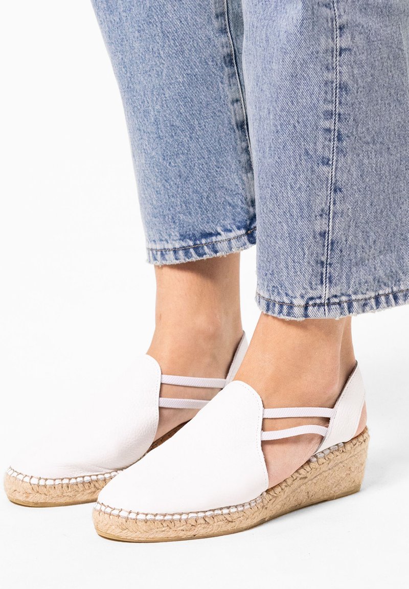 Espadrilles compensées en cuir blanc avec un talon en jute tressé. Présentent une surface lisse et deux brides autour de la cheville. Design décontracté.