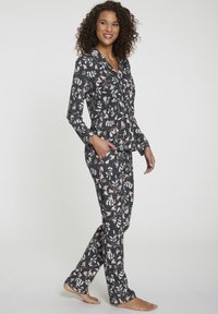Zwart bloemen pyjama set met een button-up top en broek, versierd met roze en witte bloemenpatronen, gemaakt van zachte, lichte stof.