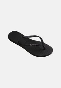 Black textured flip-flop with slim straps featuring "Havaianas" logo on the side strap, displayed against a plain light background.