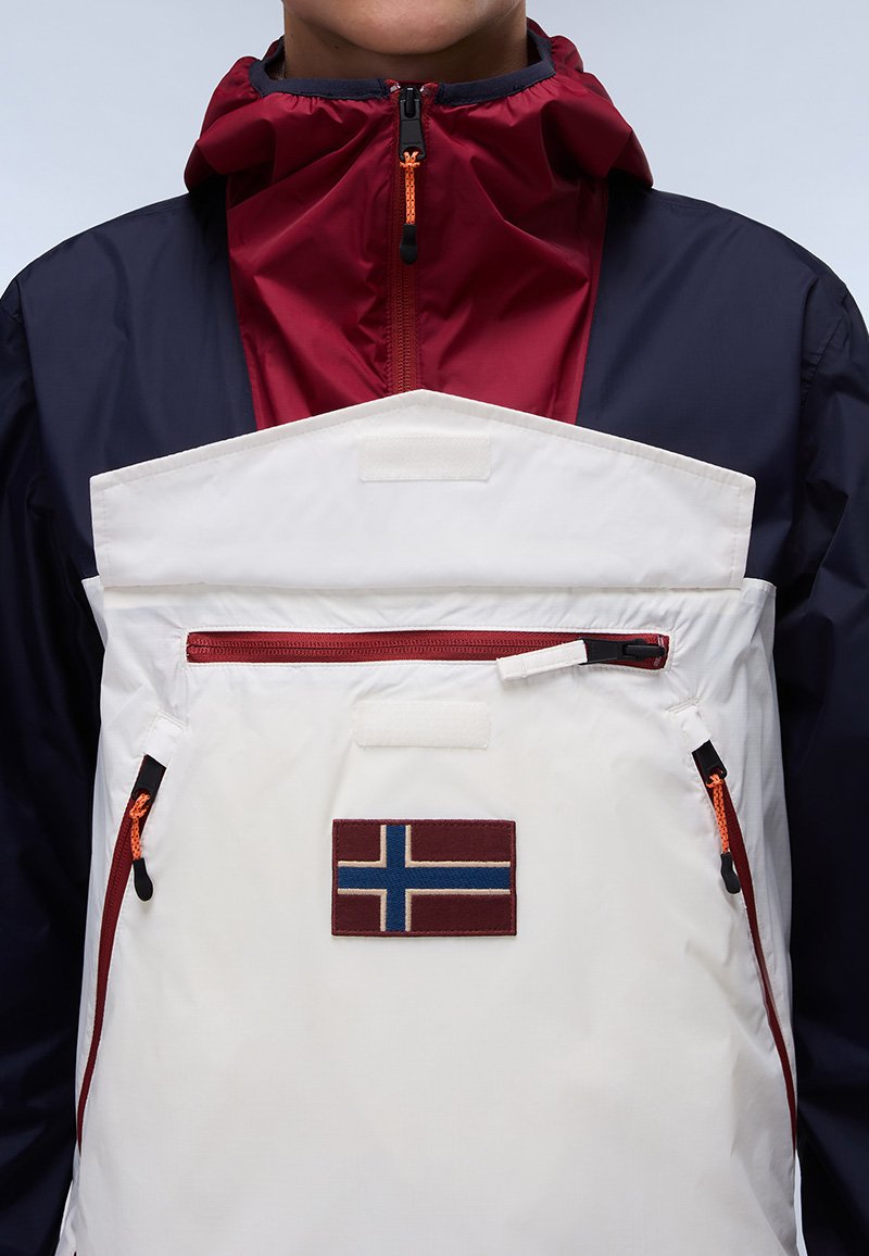 Chaqueta a bloques de color con un diseño en rojo, azul marino y blanco; cuenta con un bolsillo con cremallera y un parche de la bandera noruega en la parte frontal.