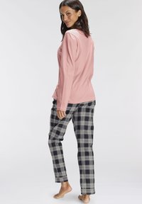 Long-sleeve pink top with a rounded hem, paired with black and white plaid pants featuring an elastic waistband and a relaxed fit.