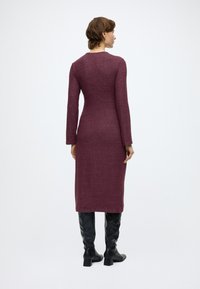 Dopasowana sukienka z długim rękawem w głębokim bordowym kolorze, wykonana z dzianiny, o długości do kolan, o gładkiej fakturze. Połączona z czarnymi, skórzanymi kozakami za kolano.