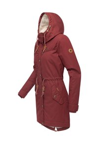 Bordowa kurtka do połowy długości z kapturem, ściągaczem w talii i futrzanym ociepleniem. Posiada detale w kolorze beżowym oraz zapinane na guziki kieszenie.