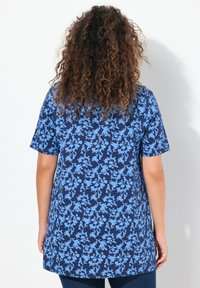 Top de manga corta azul marino con un patrón floral en azul claro; corte relajado, dobladillo curvado, textura similar al algodón, adecuado para uso casual.