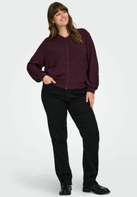 Burgundska bomber jakna s prednjim patentnim zatvaračem, rebrastim manžetama i ležernim krojem. Uparen s crnim hlačama i crnim cipelama. Suptilni sjajni detalji.