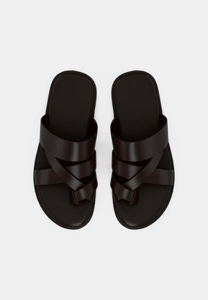 Sandales en cuir noir avec larges brides croisées et boucle pour l'orteil, conçues pour un usage décontracté, vues de dessus sur fond blanc.