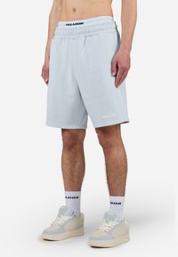 Lys blå, knæ-lange shorts lavet af blødt stof med elastisk talje. Har et logo på den nederste søm og en afslappet pasform.