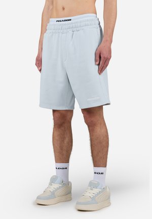 Ljusblå, knälånga shorts gjorda av mjukt tyg med resår i midjan. Har en logotyp vid den nedre fållen och har en avslappnad passform.