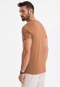T-shirt corto marrone a maniche corte realizzato in cotone, con scollo tondo, texture liscia e design aderente, mostrato da dietro.