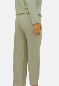 Pantalons de détente côtelés vert clair avec une coupe ample et une taille élastique. Texture douce, se resserrant vers la cheville, avec des poches latérales.