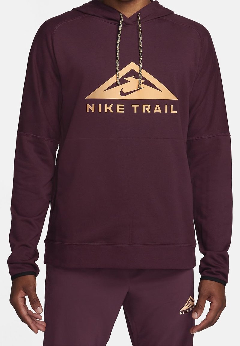 Sweat à capuche Nike Trail couleur bordeaux avec un logo triangulaire doré, capuche à cordon et poignets côtelés. Tissu lisse avec une coupe décontractée pour un confort optimal.