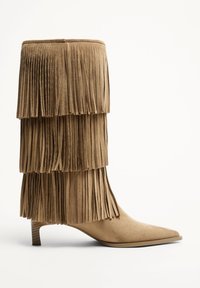 Botki z frędzlami w jasno brązowym zamszu, z warstwowymi akcentami z frędzli, spiczastym noskiem i niskim, grubym obcasem.