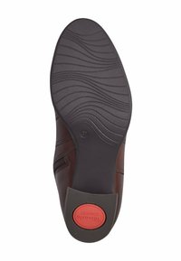 Suela de zapato de cuero marrón con goma negra texturizada. Logotipo de comodidad rojo notable en el talón y patrón de banda de rodadura ondulado para agarre.