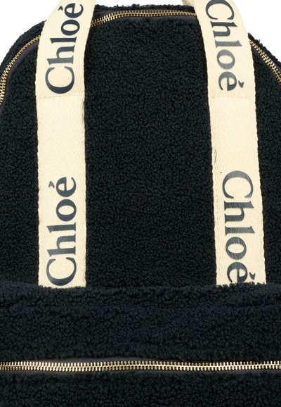 Zaino in pile nero con spallacci crema, logo 'Chloé' stampato, zip dorata e superficie testurizzata per un tocco in più.