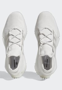 Pantofi sport albi cu un superior din tricot texturat, șireturi elastice, talpă din cauciuc și branding subtil pe branțuri și dungi laterale.