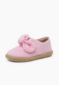 Scarpa di tela rosa con un grande fiocco sul davanti, suola in juta stile espadrille e una parte superiore morbida e testurizzata.
