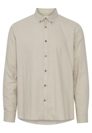 Beige långärmad skjorta gjord av lätt tyg, med en krage som knäpps och bruna knappar framtill. Slät textur, rundad fåll.