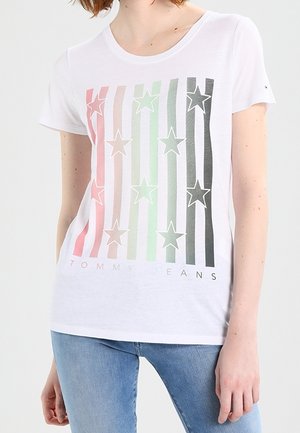 Wit katoenen T-shirt met gekleurde verticale strepen en stergrafieken. Onderaan staat de tekst "TOMMY JEANS" in het zwart gedrukt.