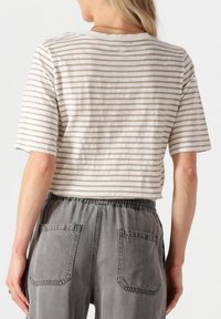 Lichtgewicht, gekropt, gestreept T-shirt in crème en taupe, met een ronde halslijn en korte mouwen. Gecombineerd met grijze elastische broek met tailleband.