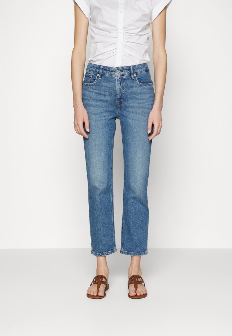 Jeans de mezclilla de pierna recta en azul claro, con un diseño clásico de cinco bolsillos y detalles de costura sutiles, combinados con sandalias marrones.