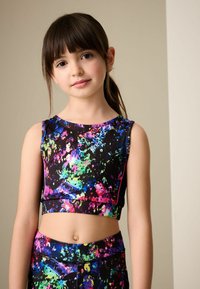 Kolorowy top na ramiączkach i dopasowane legginsy z elastycznego materiału, na czarnym tle z wyrazistymi, kolorowymi plamami w odcieniach różu, zieleni i niebieskiego.