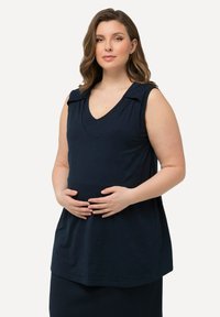 Sukienka ciążowa bez rękawów w granatowym kolorze, z dekoltem w kształcie litery V, marszczonym wzorem na ramionach oraz miękkim, textured materiałem, zapewniającym luźny krój.