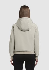 Light beige puffer jacket with a hood, ribbed cuffs, and hem. Smooth texture and minimalist design. Back view shows no visible branding.