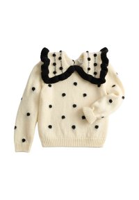 Crèmekleurige gebreide trui met zwarte stippen en een grote geplooide kraag afgezet met zwart.