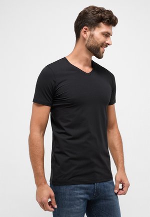 Zwarte korte mouw V-hals t-shirt gemaakt van een zachte, gladde stof, met een getailleerd ontwerp en schone randen, gecombineerd met spijkerbroeken.