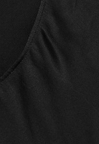 Tissu noir au toucher lisse, présentant de légères rides et un design élégant. Les bords sont finement cousus pour plus de durabilité.