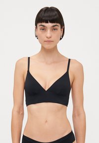 Black bralette with a V-neck design, made of smooth fabric. Features adjustable thin straps and a seamless finish for comfort.