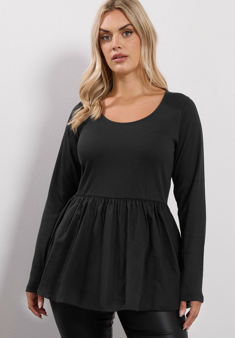 Musta pitkähihainen paita, jossa on ribbitetty pinta ja levenevä peplum-silhuetti. Pyöreä kaula-aukko ja sileä kangas vartalon osassa.