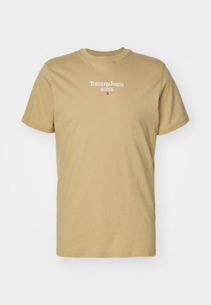 Camiseta de manga corta beige con "Tommy Jeans ©1985" y pequeño logo rojo, blanco y azul centrado en el pecho.