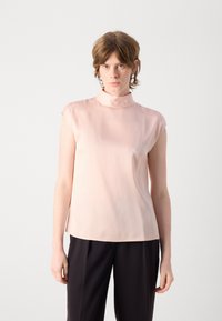 Blusa senza maniche in tessuto rosa chiaro con colletto alto. Il design presenta una texture liscia e una vestibilità comoda, abbinata a pantaloni scuri.