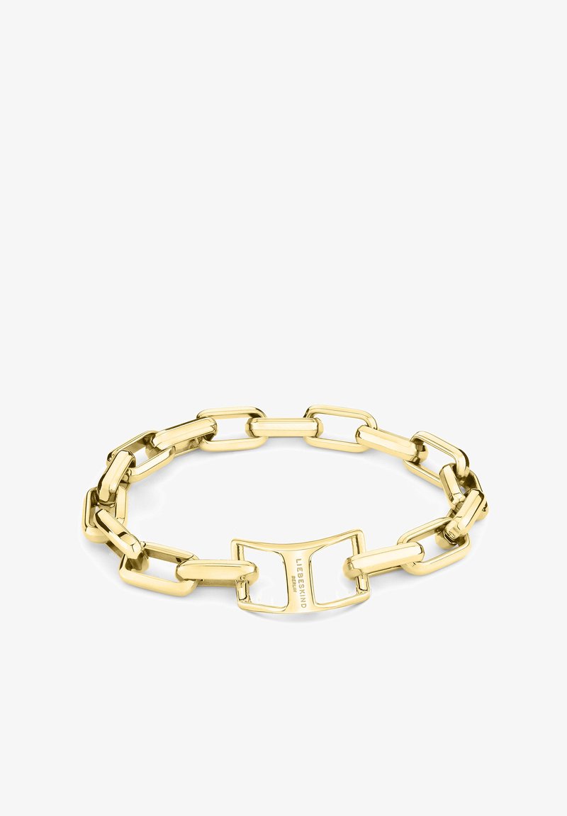 Bracelet en métal doré avec des maillons rectangulaires et un fermoir unique portant le nom de la marque, texture lisse et finition brillante.