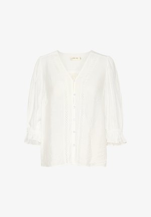 Vit bomullsblus med V-ringning, knappstängning fram, flätade stickade detaljer längs placketen och puffärmar med elastiska manschetter.