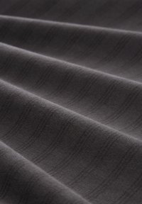 Ciemnoszara, teksturowana tkanina z subtelnymi poziomymi paskami, prezentująca miękkie fałdy i gładkie wykończenie. Idealna do tapicerki lub odzieży.