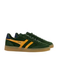 Green suede sneakers featuring orange stripes, a navy blue heel counter, and a gum rubber sole. Branding is visible on the side.